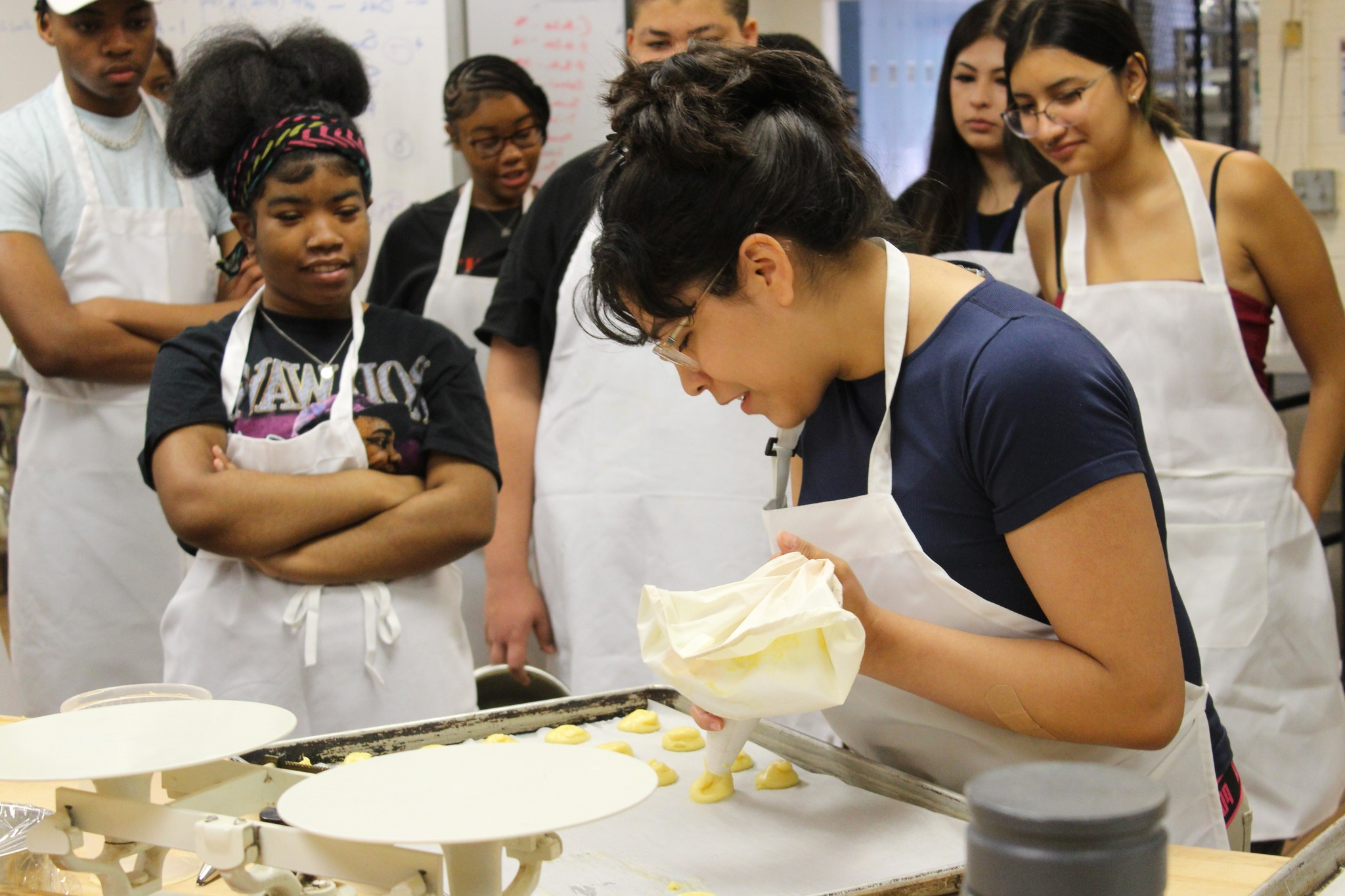 A latina student creates their culinary treat during class