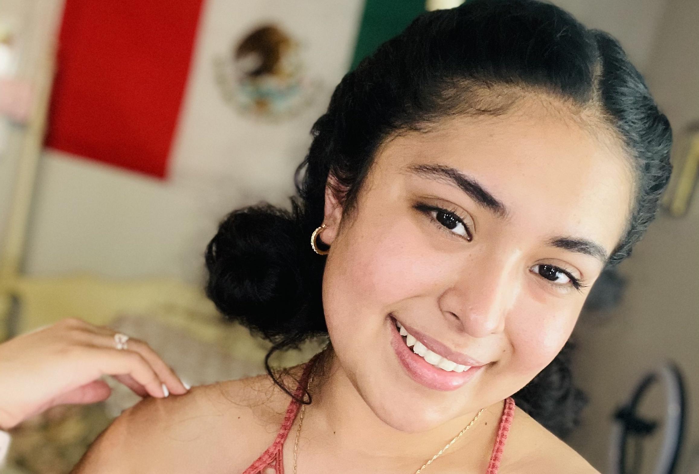 Perla Maldonado smiles for the camera with a Mexican flag in the background